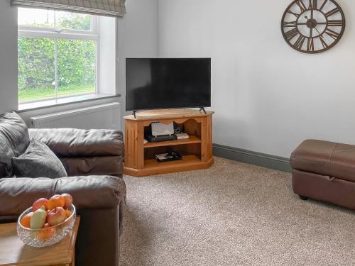 a living room with a couch and a flat screen tv at Old Master's Cottage in Leven