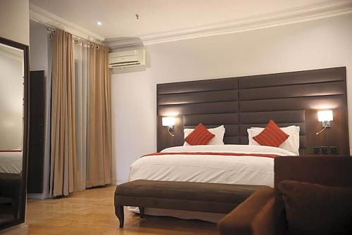 a large bedroom with a large bed with red pillows at Bolton White Hotel in Abuja