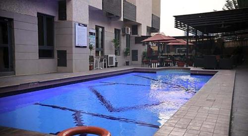 a large blue swimming pool in front of a building at Bolton White Hotel in Abuja