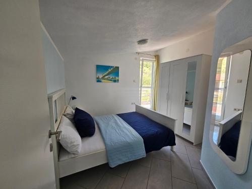 a bedroom with a bed with blue sheets and a window at Apartments VillaMare in Grebaštica