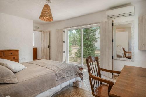 a bedroom with a bed and a table and a window at Casa do Sobreiro in Alcácer do Sal