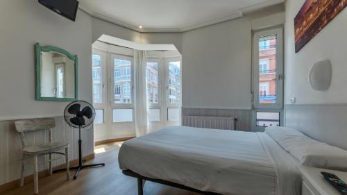a bedroom with a bed and a chair and windows at Hostal Costa Coruña in A Coruña