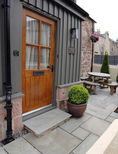 a wooden door on a building with a picnic table at Balnain Street Cottage in Inverness