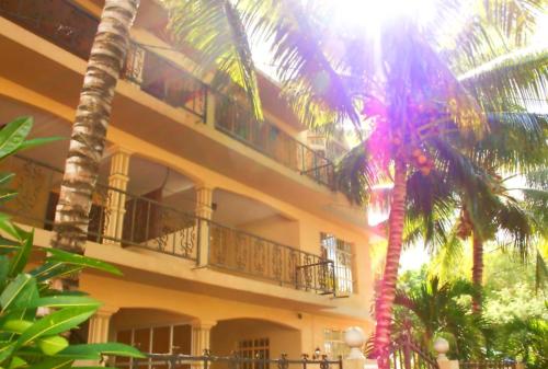 a building with a palm tree in front of it at Family apartment with pool in Trou-aux-Biches, 80 m² in Trou aux Biches