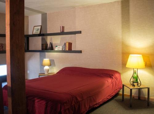 a bedroom with a red bed and two lamps at Studio confortable près de Beaumont-du-Périgord, 60 m², cheminée in Beaumont-du-Périgord