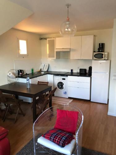 a kitchen and dining room with a table with a red pillow at Appartement cosy à Sannois de 110 m² avec jardin clôturé in Sannois
