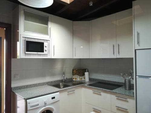 a kitchen with white cabinets and a sink and a microwave at Charming Apartment La Oliva 30 sqm + Terrace in La Oliva