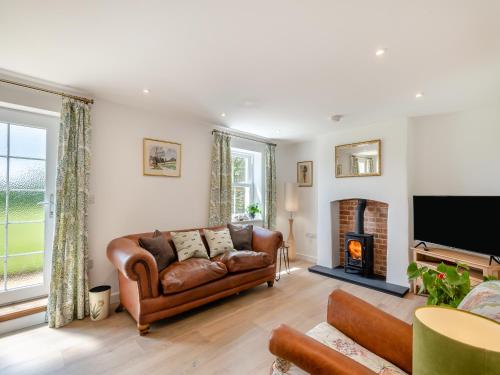 a living room with a couch and a fireplace at Manor Cottage in Longham