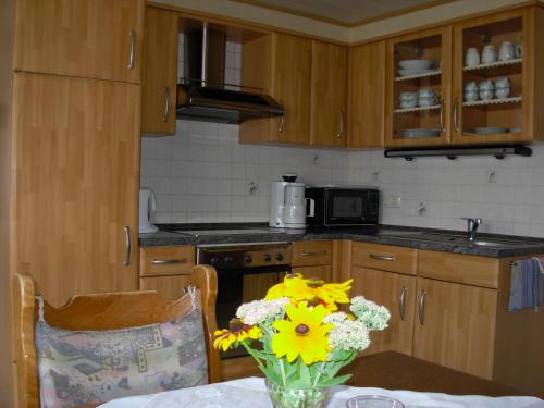 a kitchen with a table with a vase of yellow flowers at Ferienwohnung Steinebach in Daun