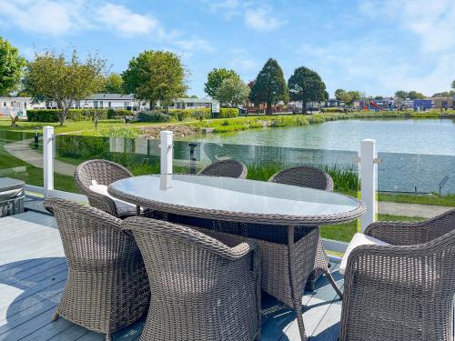 a table and chairs with a view of the water at Serenity At Lakeside - Uk51947 in Patrington