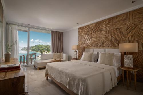 a bedroom with a large bed and a view of the ocean at Mythos Palace Resort - Adults Only in Boukari