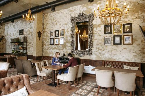 zwei Personen sitzen an einem Tisch in einem Restaurant in der Unterkunft Andersen Hotel in Dombai