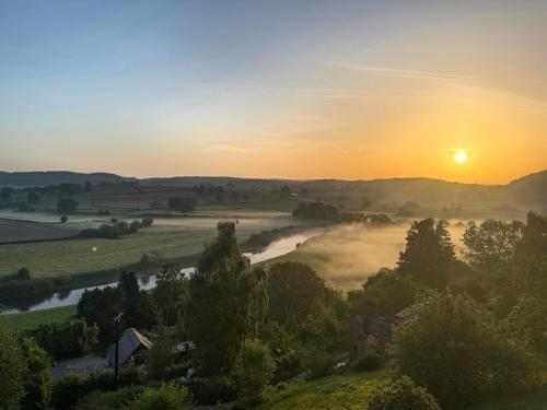 a misty sunrise over a valley with a river at Wye Nest in Fownhope