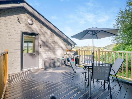 a deck with a table and an umbrella at Wye Nest in Fownhope