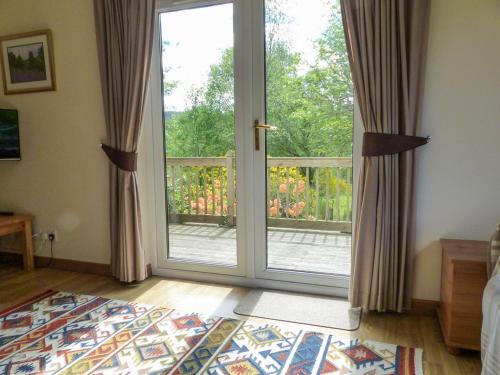 a bedroom with a sliding glass door with a balcony at Bo Nan Taigh Cottage in Aberfoyle