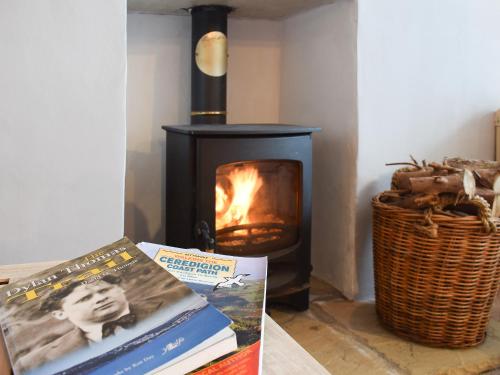 a room with a stove with books and a basket at Seadrift in New Quay