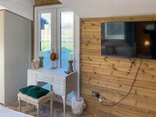 a bedroom with a wooden wall with a tv on it at Eagle Lodge in Cowbridge