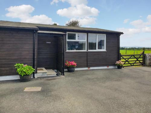 a wooden house with potted plants in front of it at Classroom Two - Uk48651 in Lifton