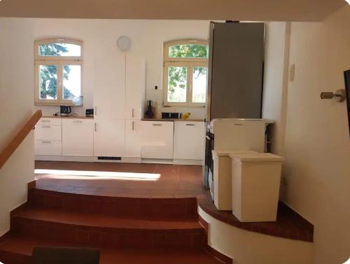 a kitchen with white cabinets and stairs in a room at Fewo-Am-alten-Bahnhof in Tangerhütte