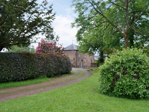 a dirt road leading to a large brick building at Gilminscroft Gatehouse in Sorn
