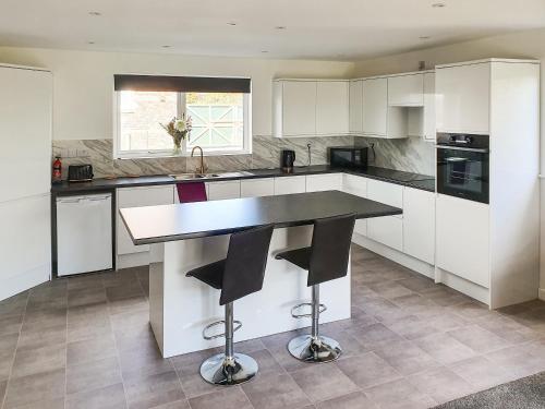 a kitchen with white cabinets and a black counter top at Classroom One - Uk48650 in Lifton