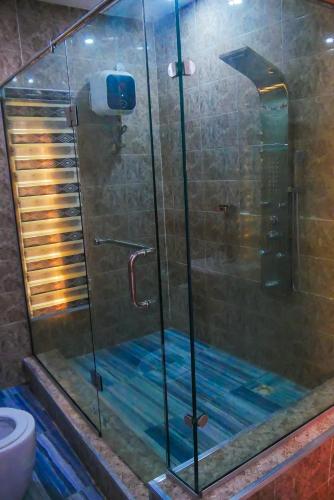 a shower with a glass shower door in a bathroom at Joebrown Palace Hotel & Suite in Akitan