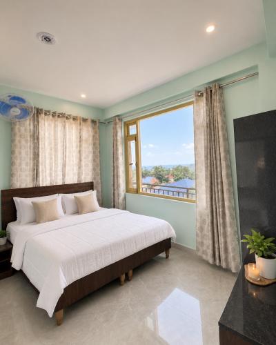 a bedroom with a bed and a large window at Aurelia Ridge in Bīr