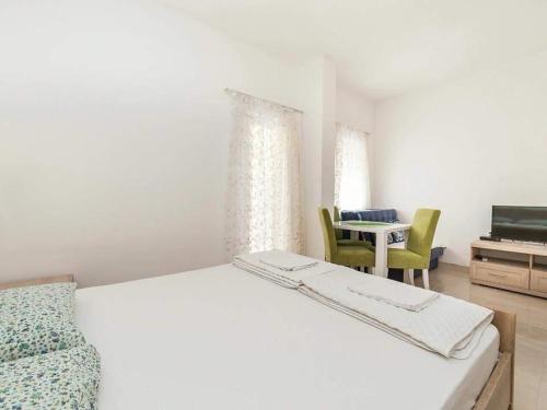 a white bedroom with a bed and a table and chairs at Studio Apartment in Kaluđerac