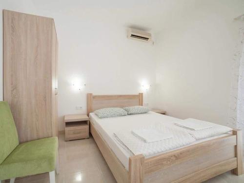 a bedroom with a bed and a green chair at Studio Apartment in Kaluđerac