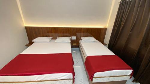 two beds in a small room with red and white at Sri Durga Residency in Subrahmanya