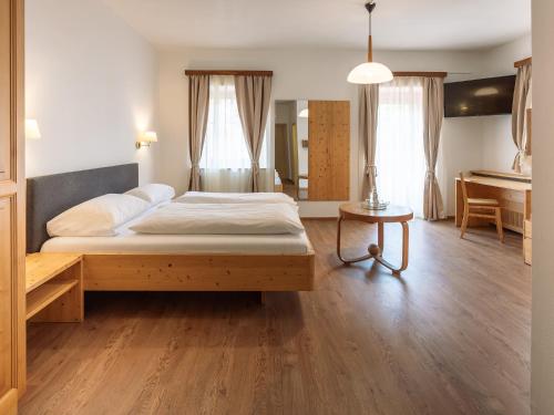 a bedroom with a large bed and a table at Hotel Hello in Monguelfo