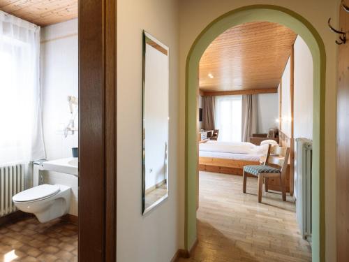 a bathroom with a toilet and a bed in a room at Hotel Hello in Monguelfo