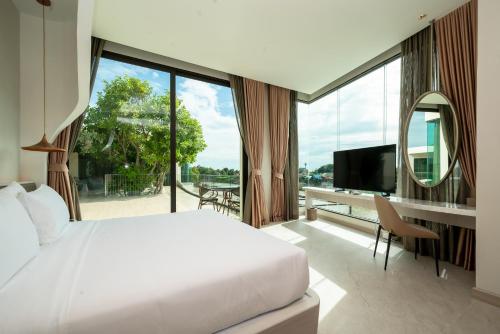 a bedroom with a white bed and a large window at The Rachata at Ayothaya in Ban Khlong Takhian