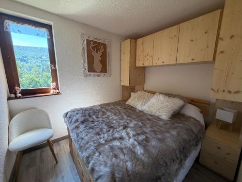 a bedroom with a bed and a window and a chair at Le cocon dans les nuages in Lélex