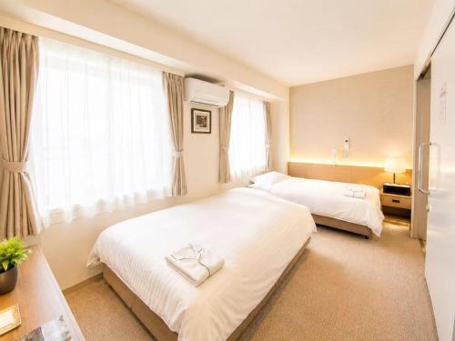 a hotel room with two beds and windows at Saga Idaimae Green Hotel in Saga