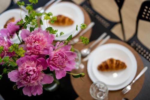 a table with two plates of food and pink flowers at Friendhouse Residence in Krakow
