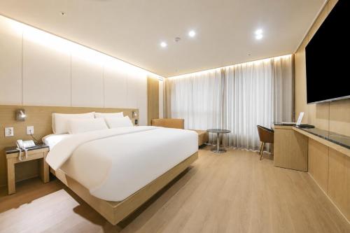 a bedroom with a large white bed and a television at 제니스 호텔 in Jecheon