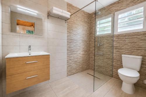 a bathroom with a toilet and a glass shower at La Kaz' Mathosie in Saint-André