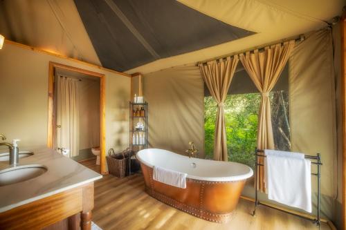 a large bathroom with a tub and a window at Elewana Sand River Mara in Talek