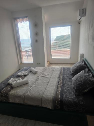 a bedroom with a large bed with two windows at Seaview apt. 3 complex Karia in Kavarna