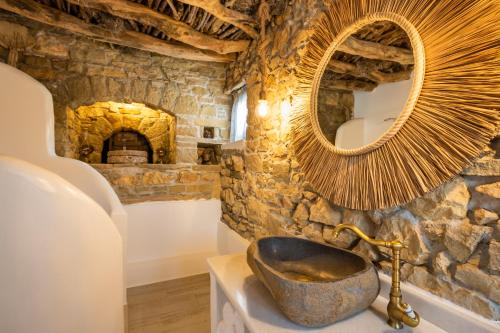 a stone bathroom with a large mirror and a sink at Mythos Villa Above the Sunset in Karpathos