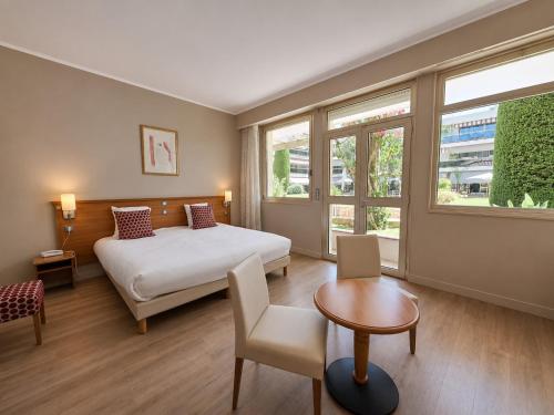 a hotel room with a bed and a table at The Originals Boutique, Hôtel Les Strélitzias in Juan-les-Pins