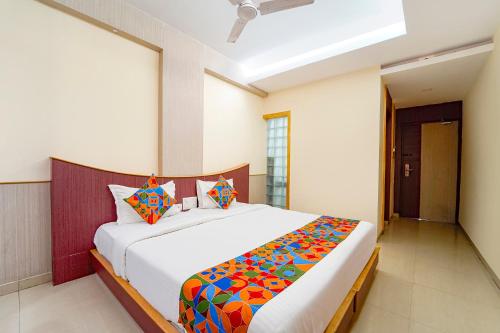 a bedroom with a large white bed with colorful pillows at FabHotel Grand Gunas in Coimbatore