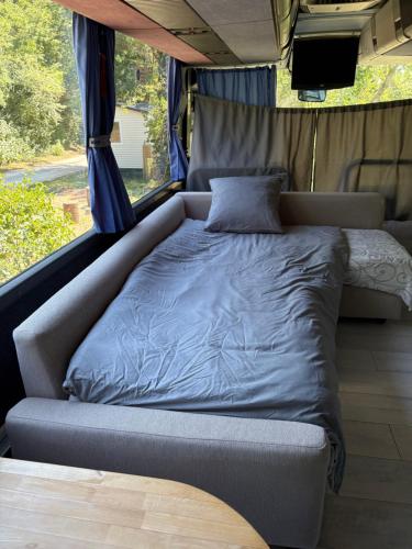 a bed in the back of a van with a tv at Unique et Insolite Bus Iliade in Bourg