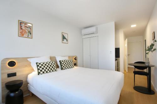 a white bedroom with a white bed and a table at Sweetly Bordeaux Mérignac Aeroparc in Mérignac
