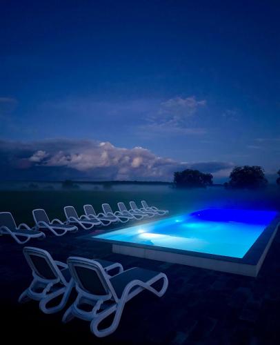 a group of chairs and a swimming pool at night at Blisko Natury Jacuzzi & Sauna in Pisz