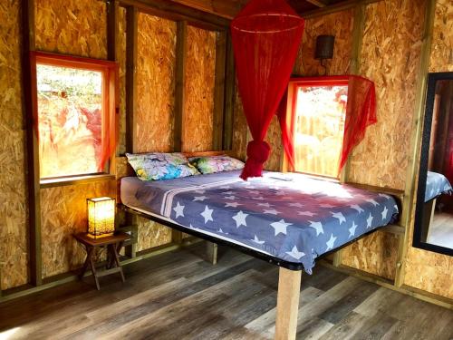 a bed in a log cabin with two windows at Calme et Nature in Saint-Leu