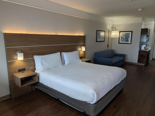 a hotel room with a bed and a blue chair at Holiday Inn Express & Suites Galveston West-Seawall by IHG in Galveston