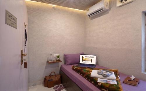 a small room with a bed with a laptop on it at The Cubicle in Haldwāni