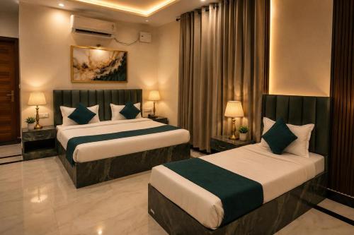 a hotel room with two beds and two lamps at Hotel KS Palace in Varanasi